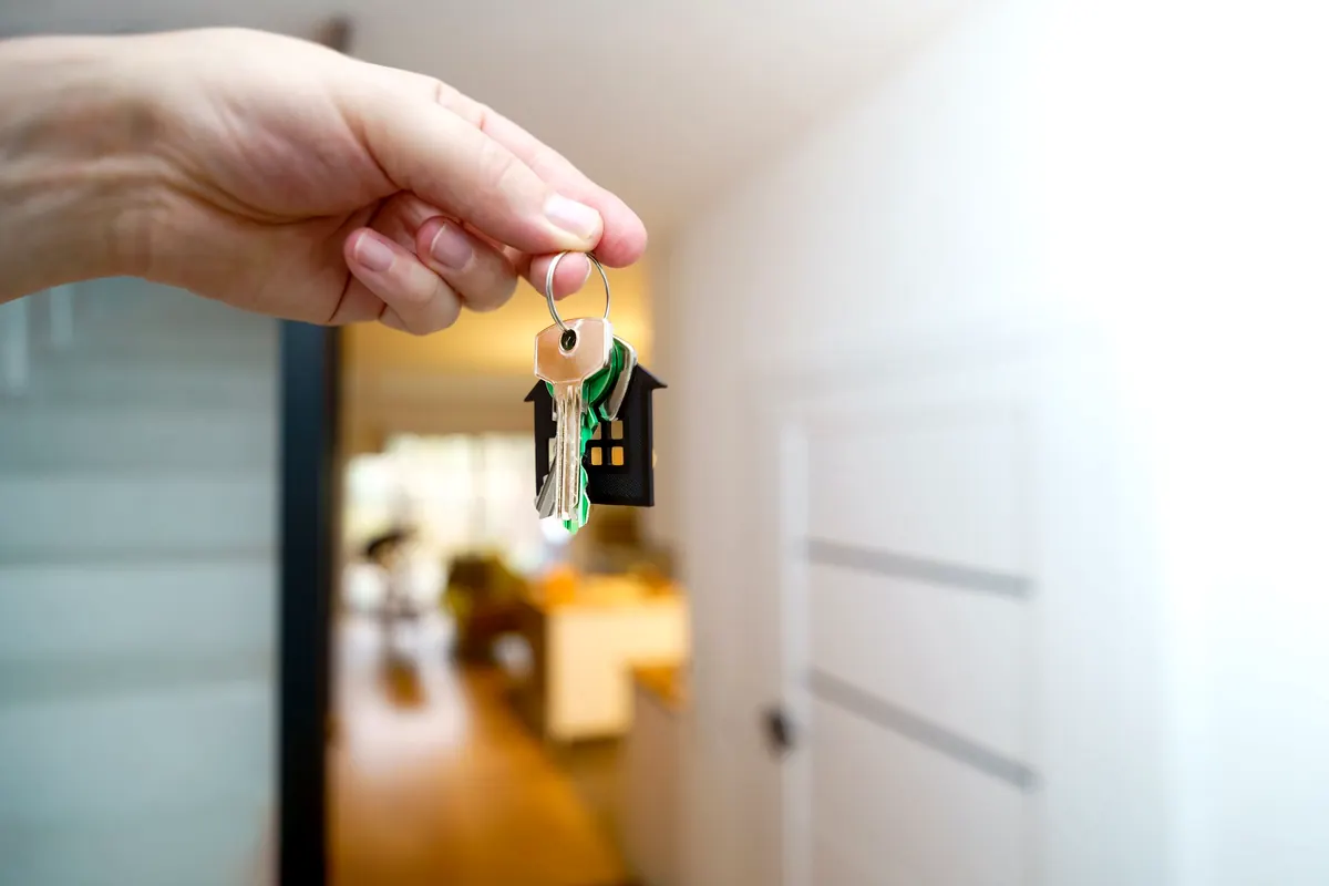 Hand holding house keys inside an apartment